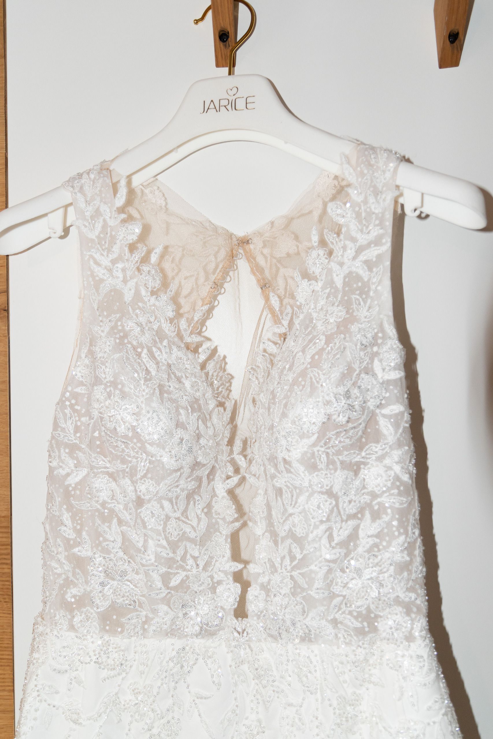 weißes Hochzeitskleid mit Perlen verziert. Kleid hängt noch am Kleiderbügel.