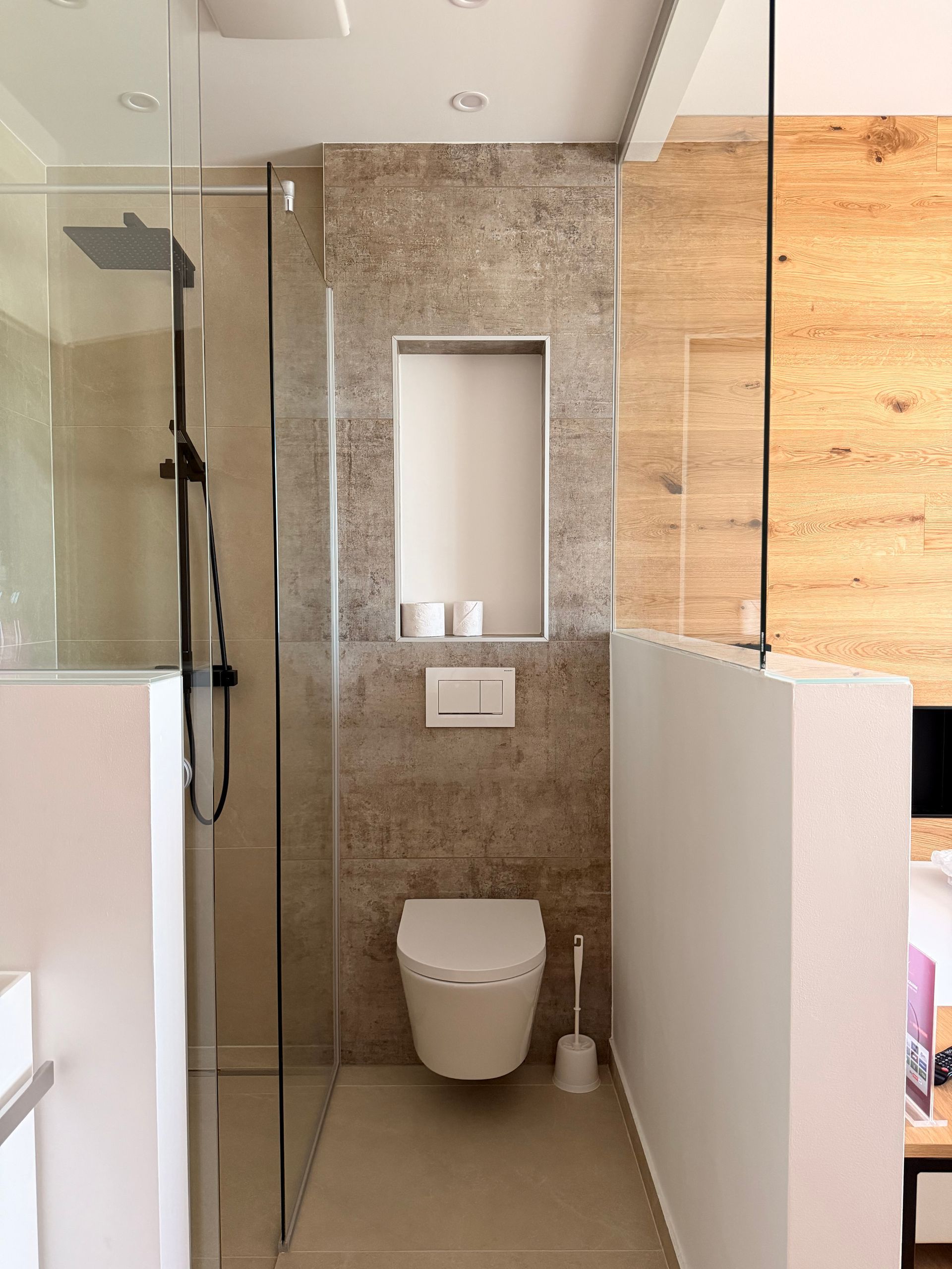 offenes Badezimmer mit Naturstein verfliest und Regendusche. warme Beleuchtung, modern eingerichtet.