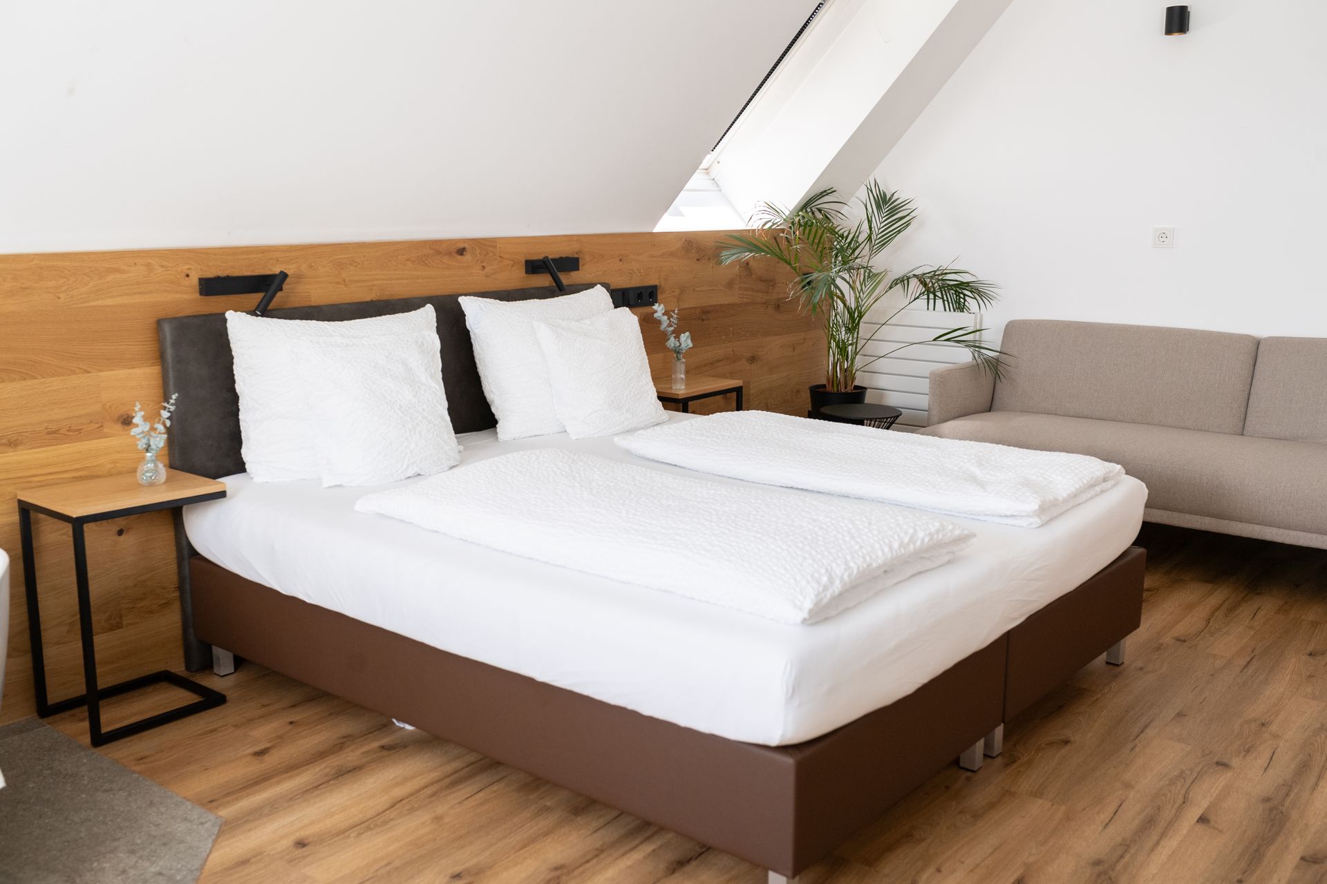 Rooftop Suite mit großem Doppelbett und Sofa. Dachfenster für viel Licht. Echter Parkett Boden und Wandverkleidung aus Holz.