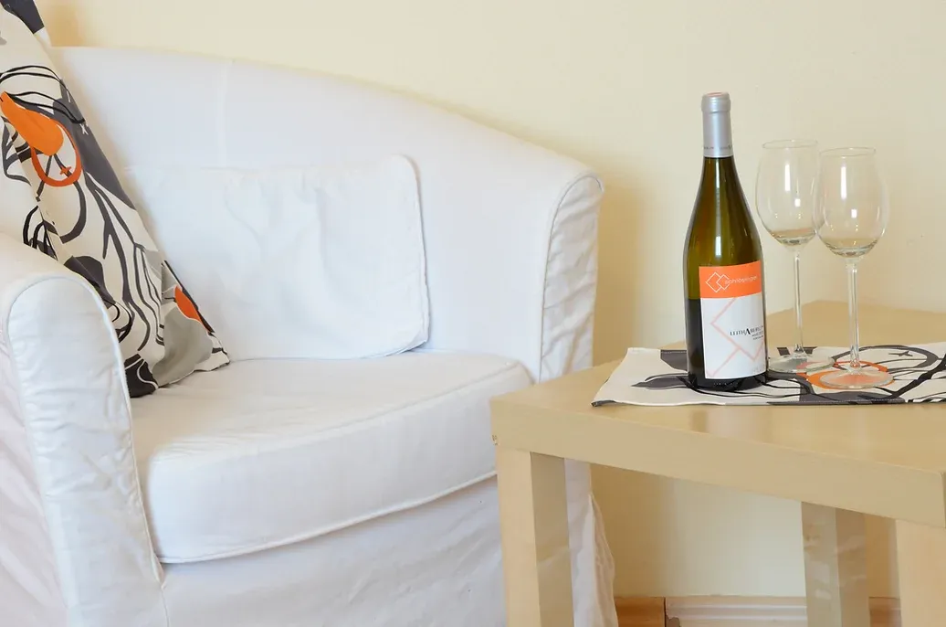Loungesessel im Doppelzimmer mit kleinem Beistelltisch und darauf lokaler Wein.