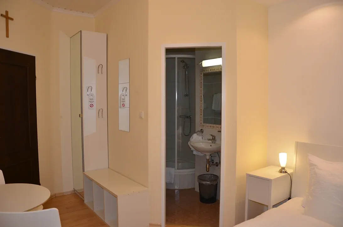 Kompaktes Doppelzimmer warm eingerichtet. Eingang zum Badezimmer.