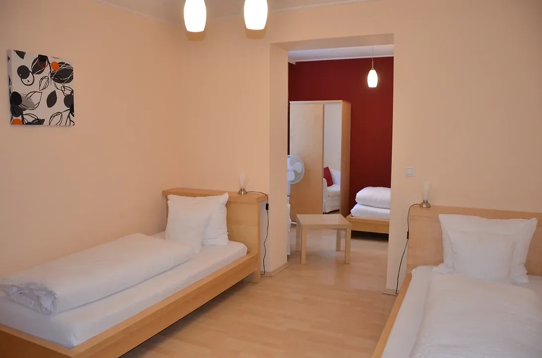 Dreibettzimmer, warm eingerichtet. Mit drei getrennten Betten.