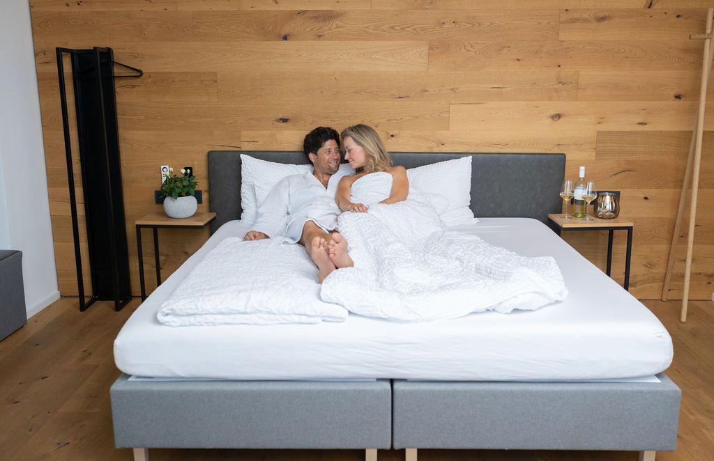 Großes Doppelbett in Appartment 8, Pärchen auf dem Bett. Das Bett steht an einer