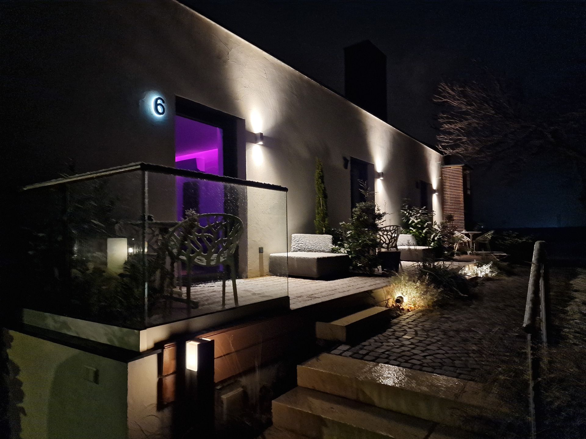 geislerAppartment Terrassen von Appartment 6, 7, 8 bei Nacht und beleuchtet. Terasse aus Holz, darauf graue Polstermöbel.