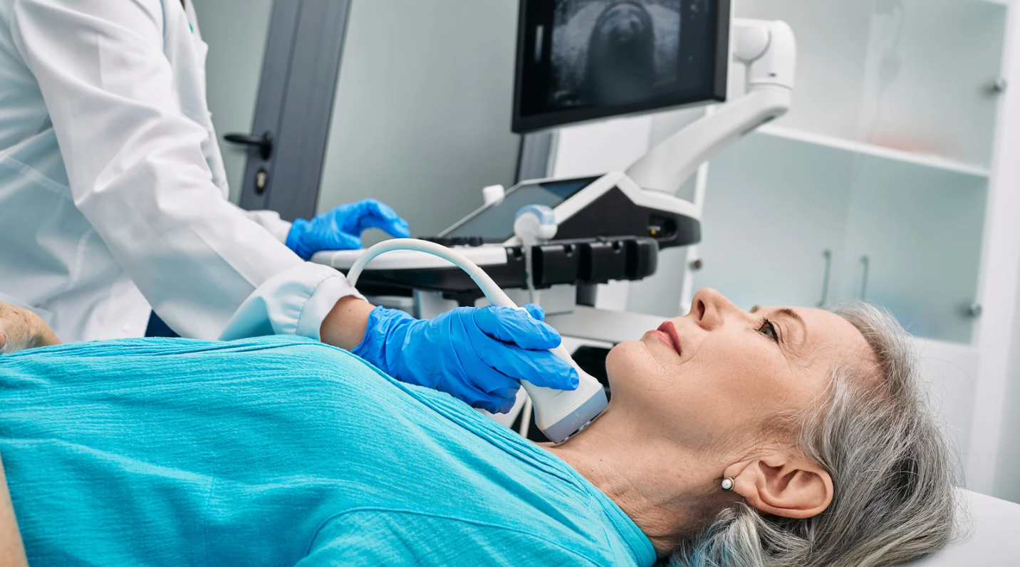 Patient undergoing a neck ultrasound in a medical clinic while a clinician examines the area
