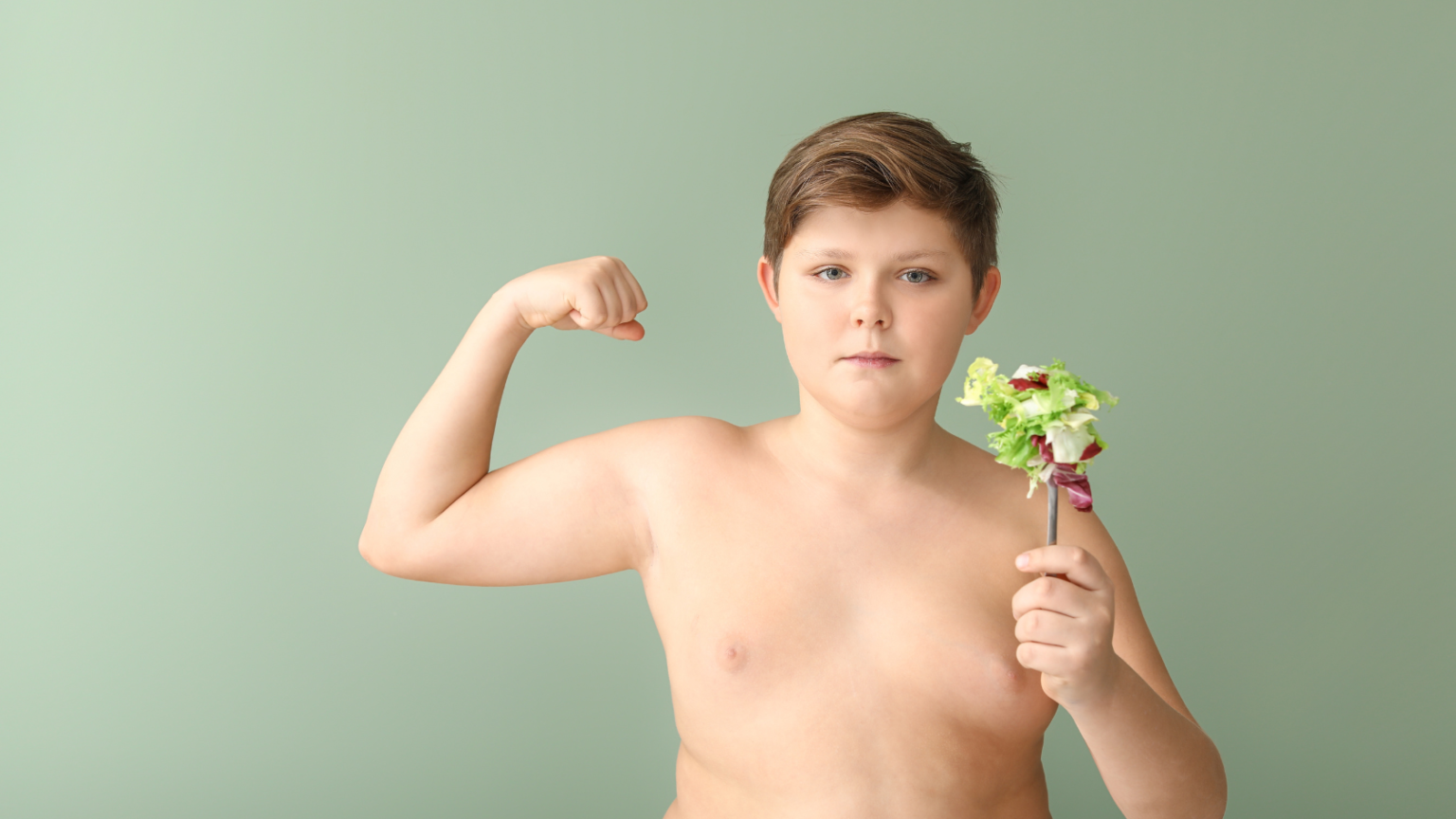 Boy flexing one arm while holding a small bouquet against a green background