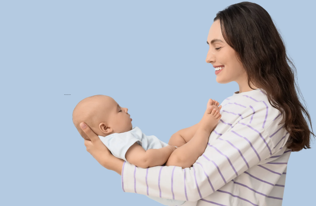 Mulher segurando um bebê sorridente contra um fundo azul-claro.
