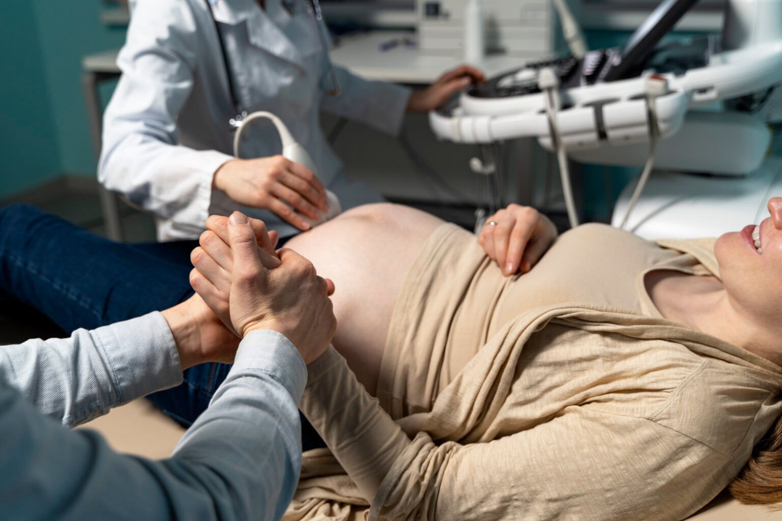 Medical staff assisting a pregnant patient on a hospital bed during an exam