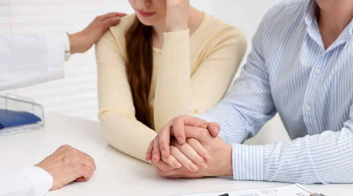 Pessoas em uma sessão de aconselhamento de mãos dadas ao redor de uma mesa