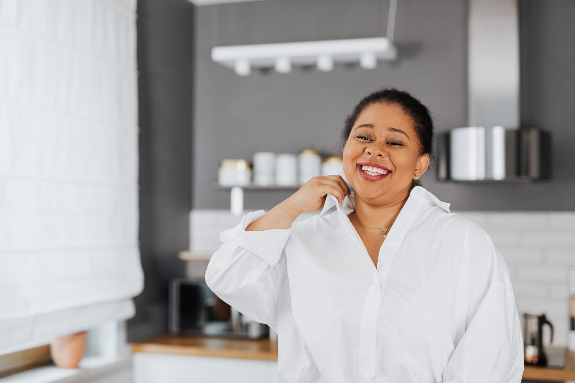 Smiling person in a white shirt standing in a modern kitchen