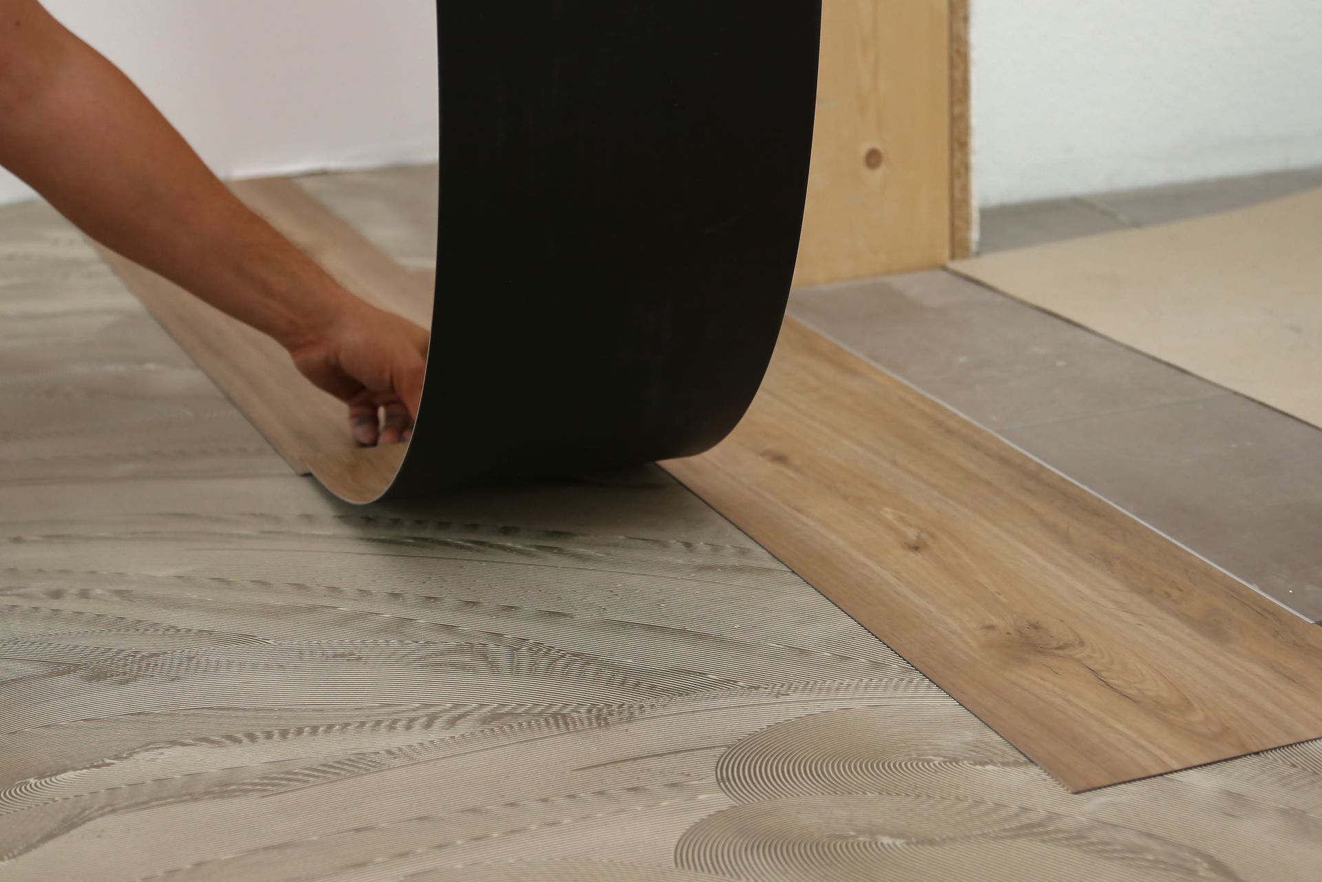 A person is laying a piece of vinyl flooring on the floor. A person is laying a piece of vinyl flooring on the floor.