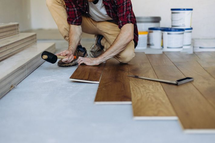 A man is installing a wooden floor in a room.