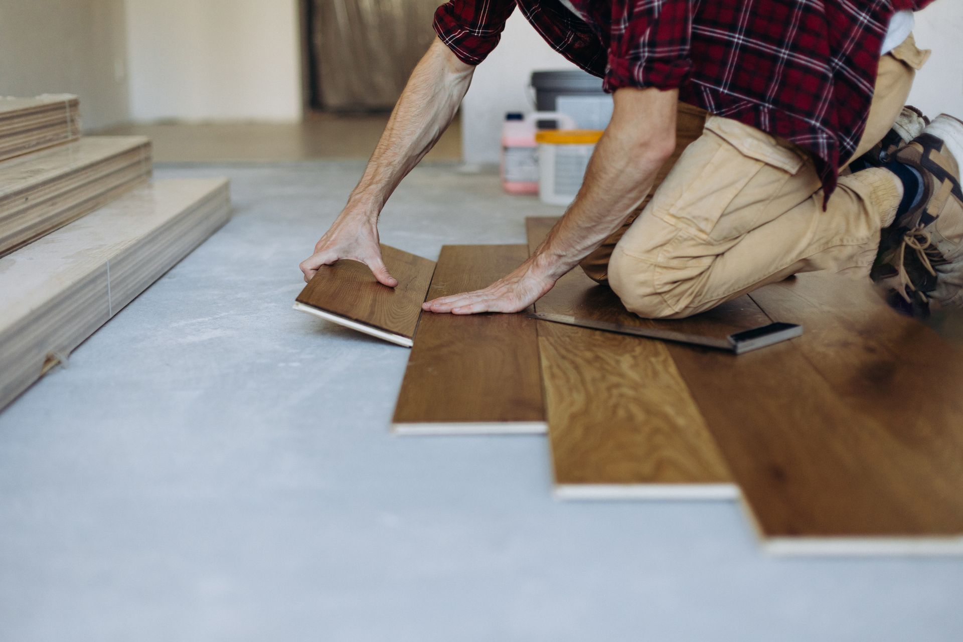 A man is kneeling down to install a wooden floor. A man is kneeling down to install a wooden floor.