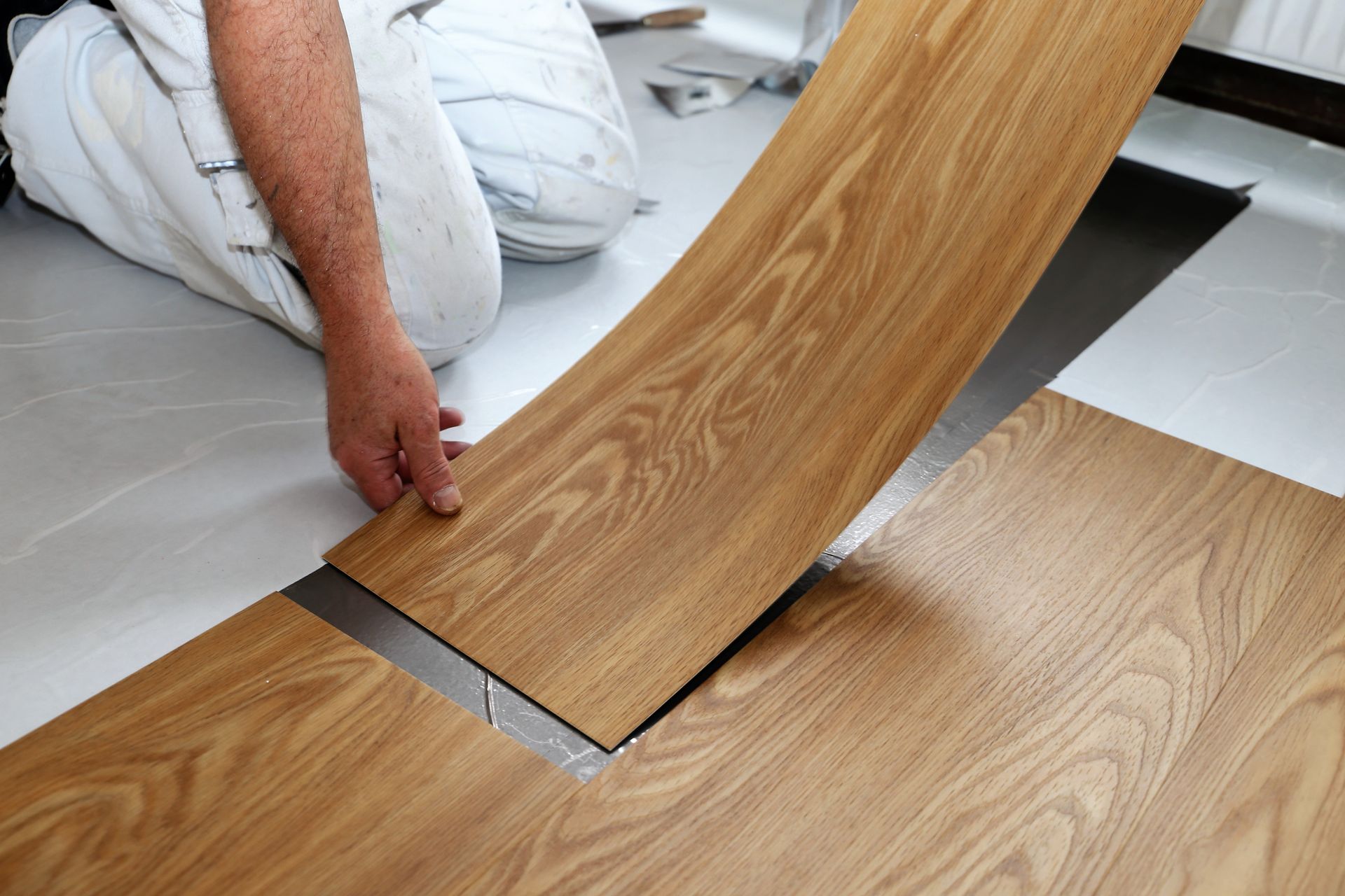 A man is laying a piece of vinyl flooring on the floor. A man is laying a piece of vinyl flooring on the floor.
