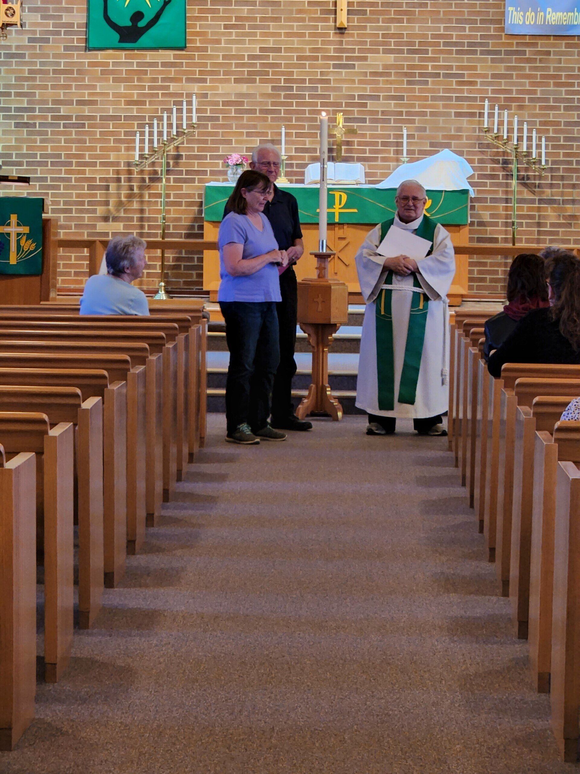 A man in a green and white robe stands in a church