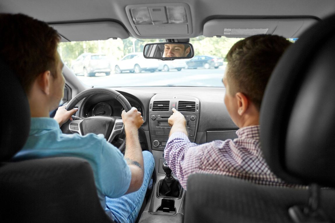 A man is teaching another man how to drive a car.