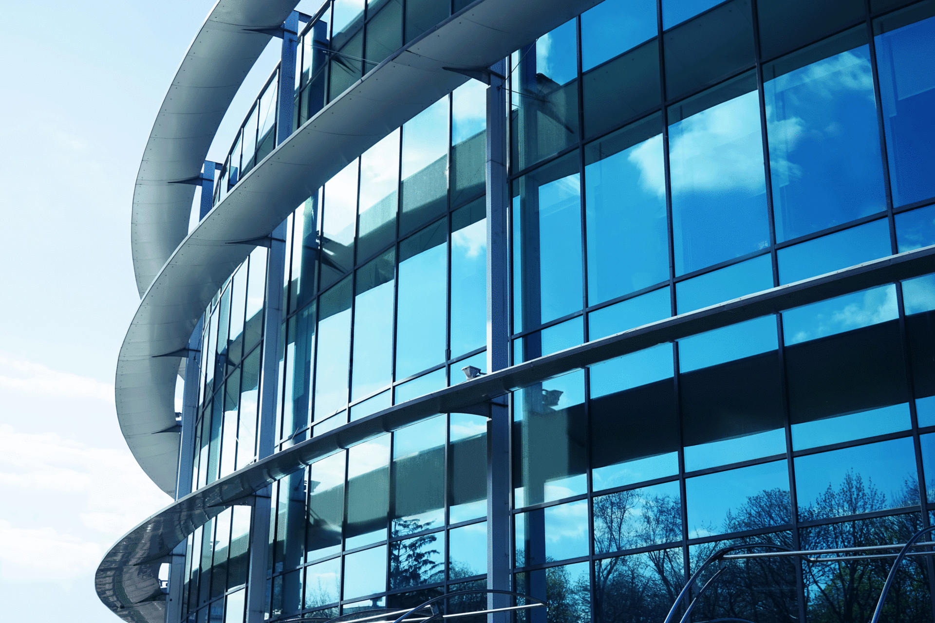 Modern office building with curved glass windows reflecting the sky.