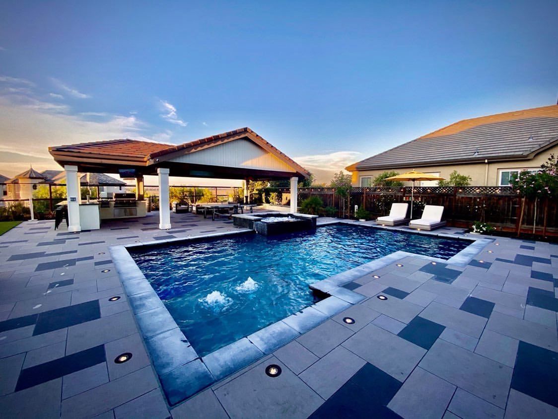 Backyard pool with a waterfall feature, patio, gazebo, and lounge chairs.