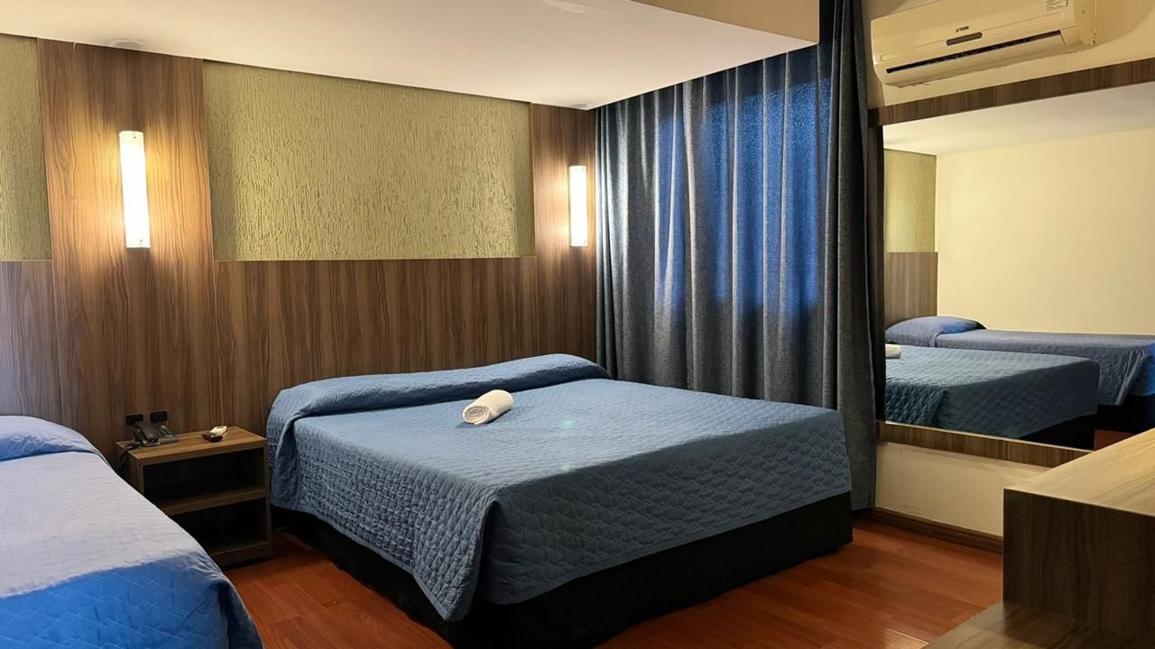Um quarto de hotel com duas camas e um espelho grande.