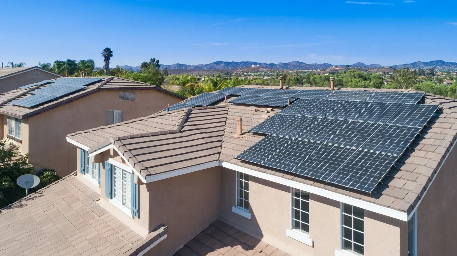 Suburban house roof with large solar panel array on a sunny day