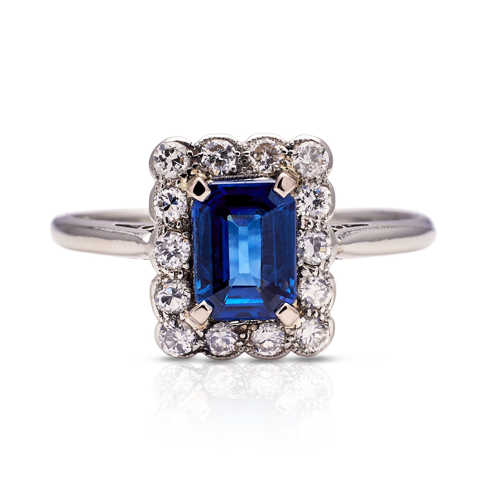 a ring with a sapphire and diamonds on a white background .