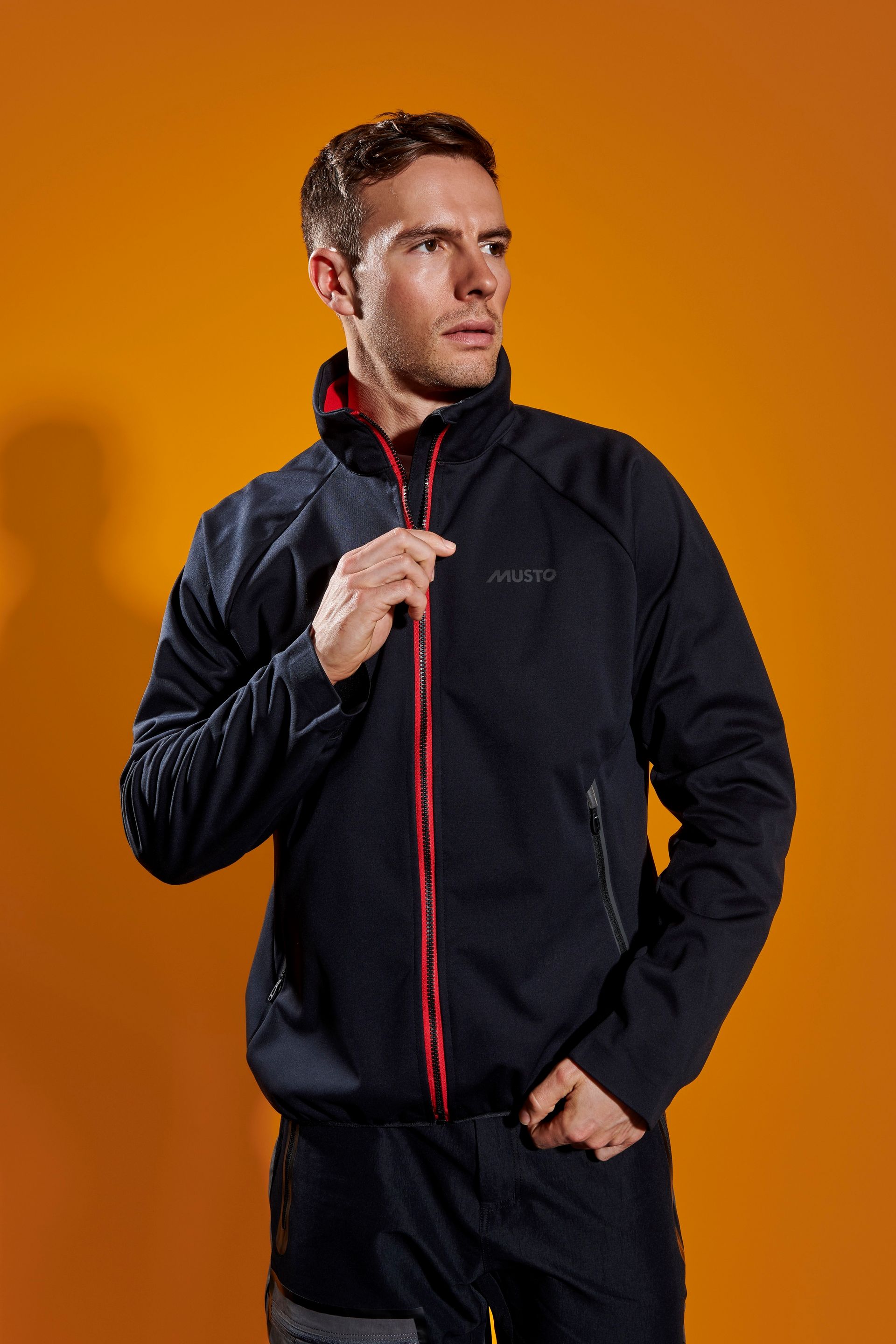 a man is wearing a black jacket with a red zipper .