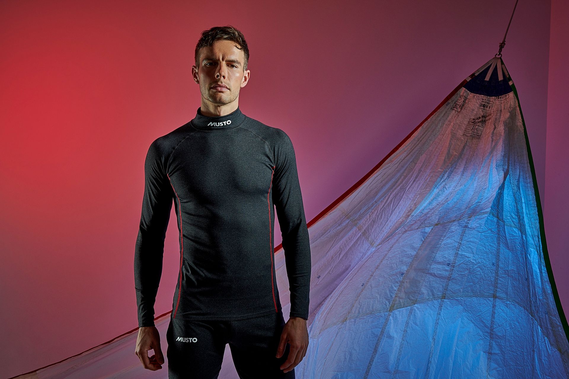 a man in a long sleeve shirt is standing in front of a sail .