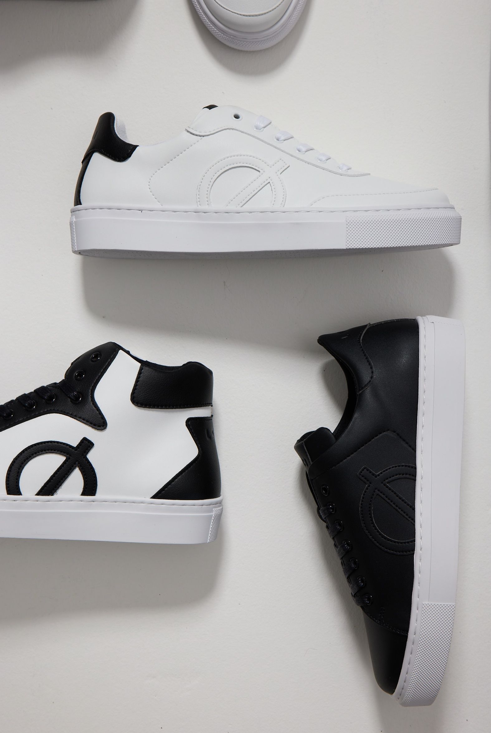 a pair of black and white sneakers on a white surface .