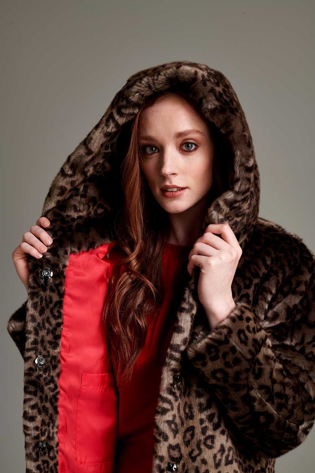 a woman is wearing a leopard print coat with a hood .