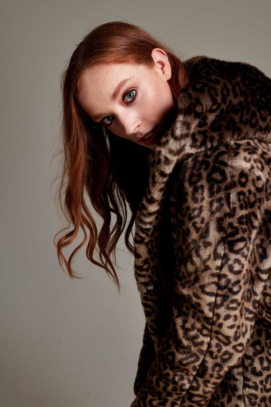 a woman with red hair is wearing a leopard print fur coat .