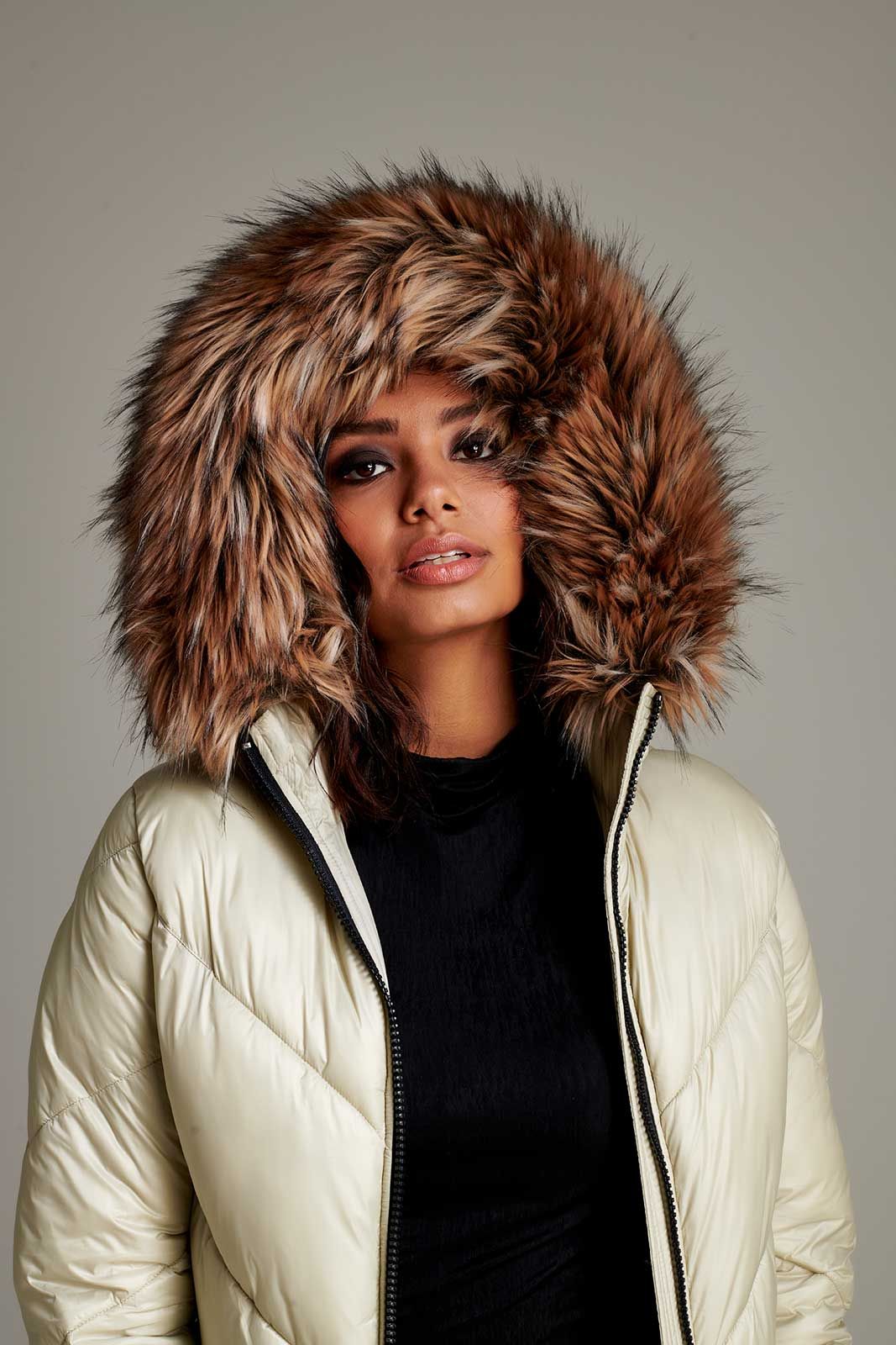 a woman is wearing a white jacket with a brown fur hood .