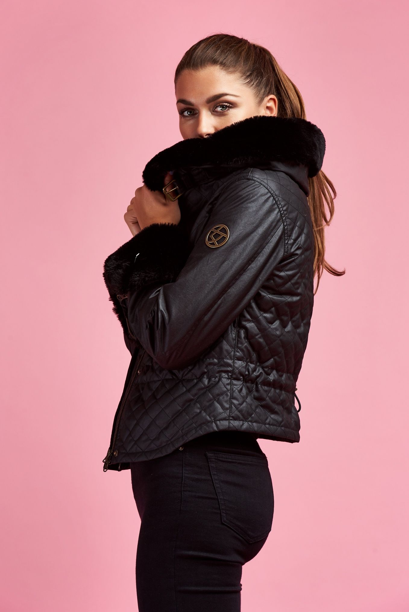 a woman is wearing a black jacket with a fur collar .