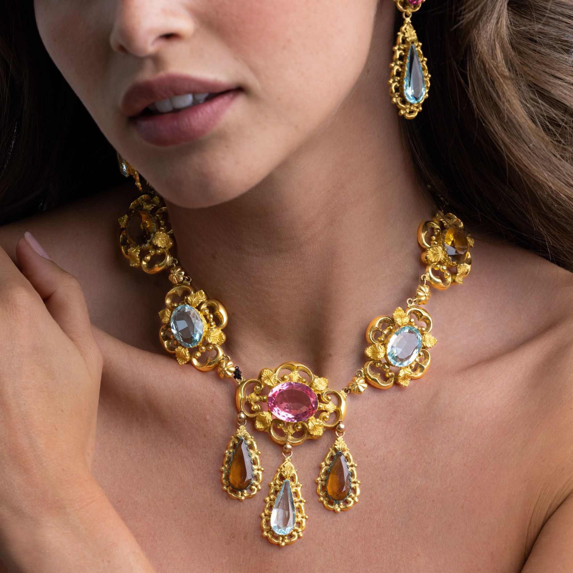 a woman is wearing a gold necklace and earrings