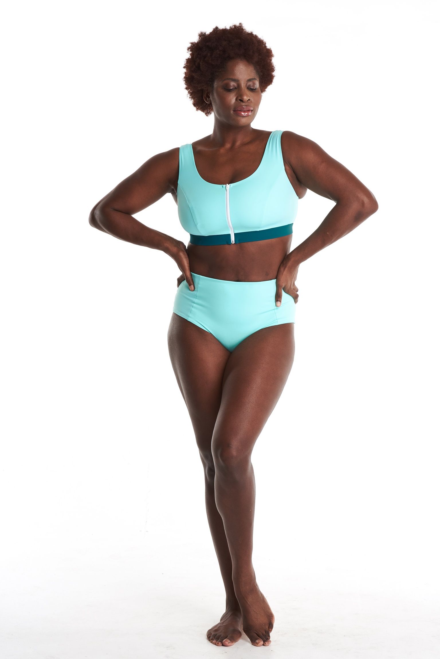 a woman in a bikini top and high waisted bottoms is standing on a white background .