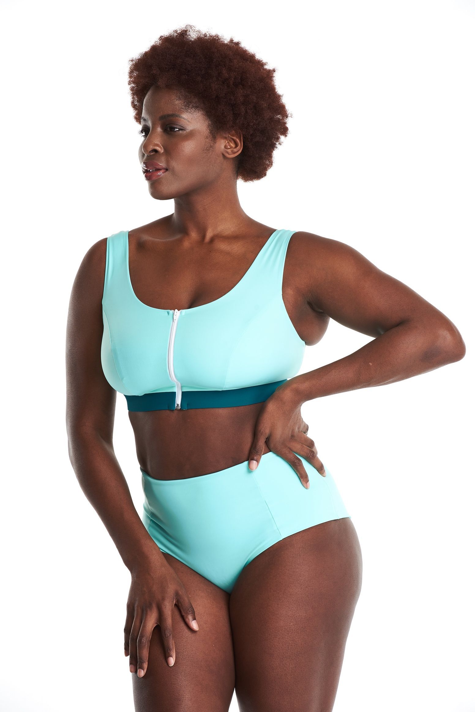 a woman is wearing a blue bikini top and high waisted bottoms .