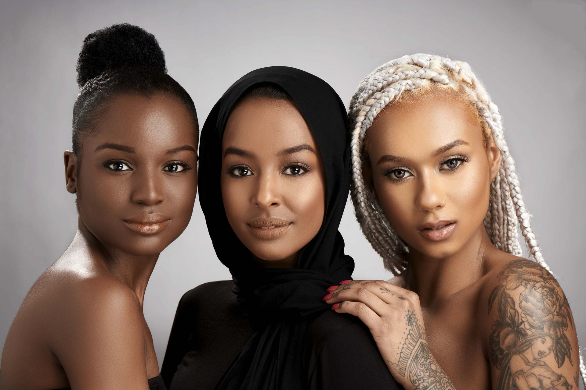 Three women of different races are posing for a picture together.