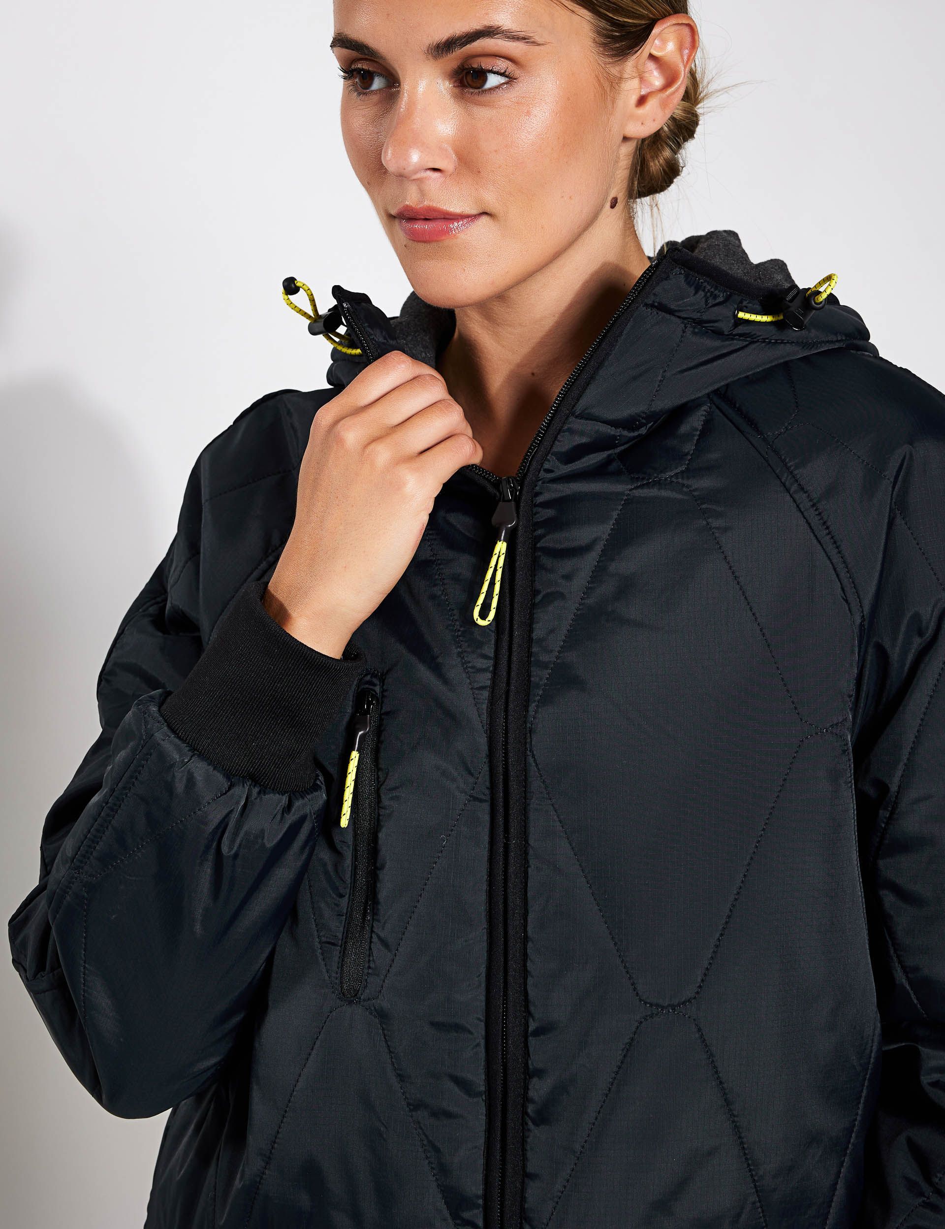 a woman is wearing a black jacket with a hood .