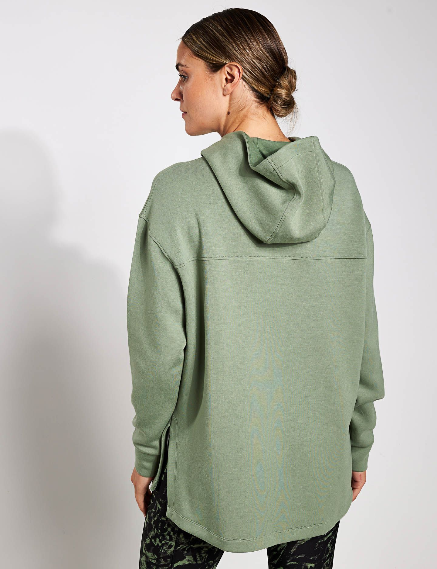the back of a woman wearing a green hoodie and black pants .