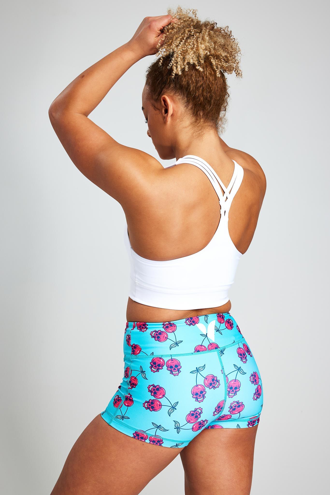 a woman is wearing a white sports bra and blue shorts with flowers on them .
