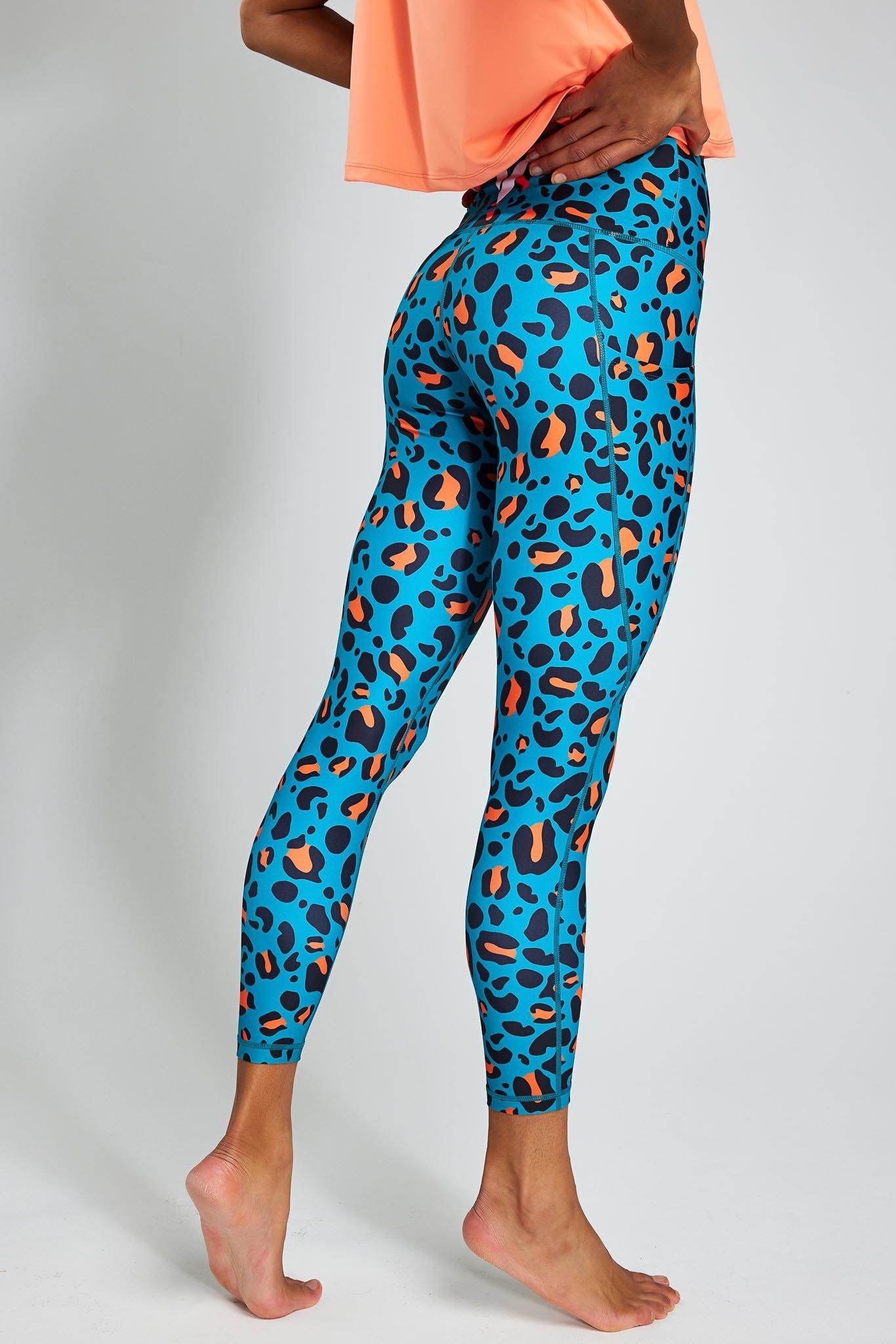 a woman is wearing a pair of blue and orange leopard print leggings .