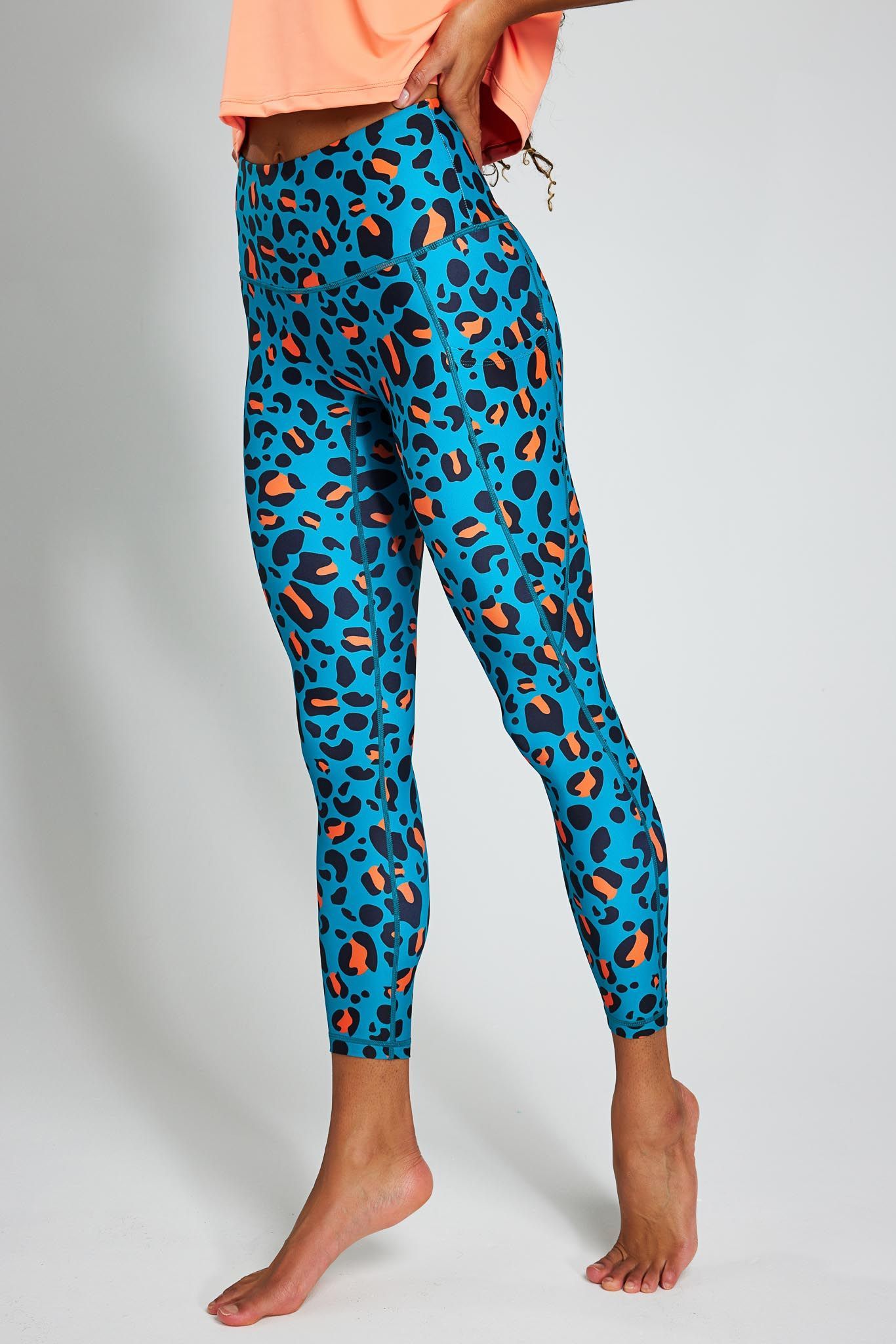 a woman is wearing a pair of blue and orange leopard print leggings .