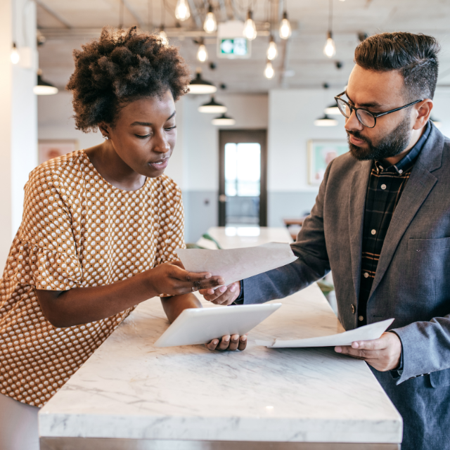 Woman and man reviewing documents and a tablet in an office setting.