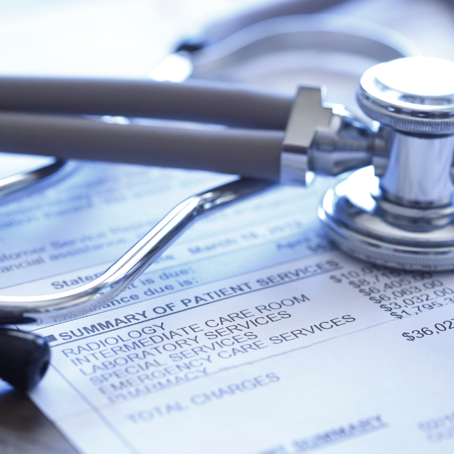Stethoscope resting on a medical bill, detailing patient services and charges.