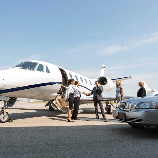 People boarding a private jet, with a limousine nearby on a sunny tarmac.