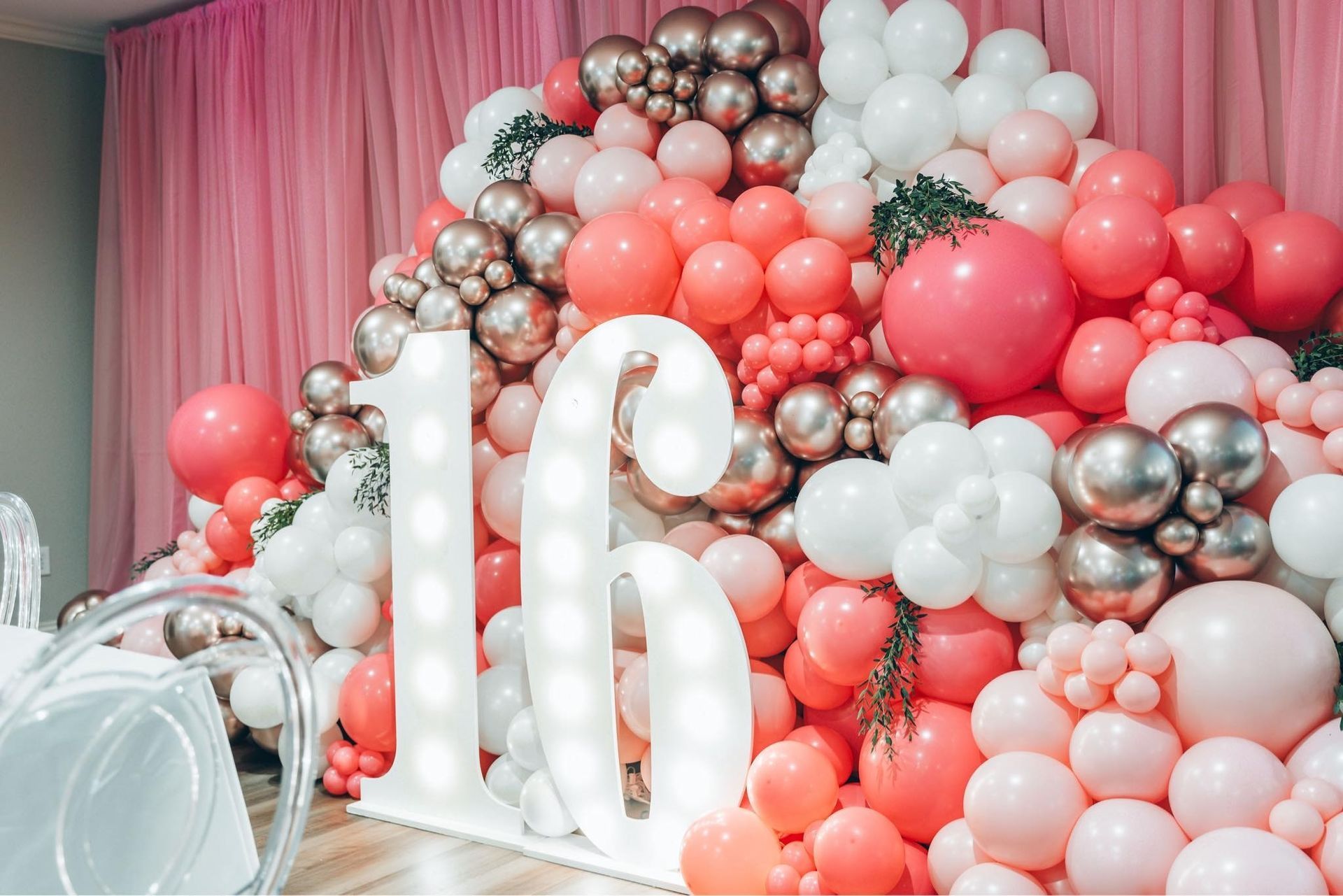 A chair is surrounded by black and gold balloons and a large number 39.