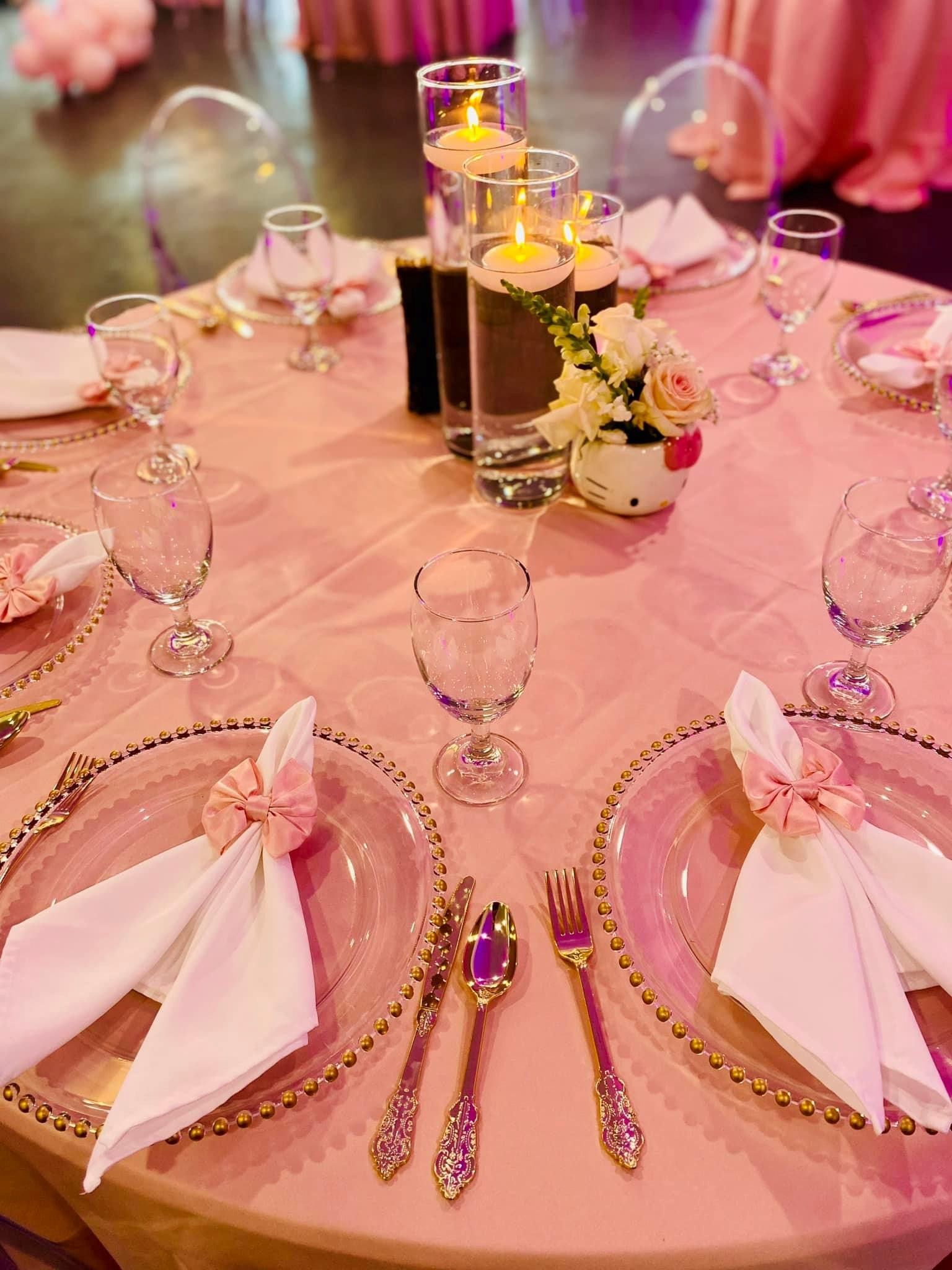 A table set for a wedding reception with plates , utensils , and candles.