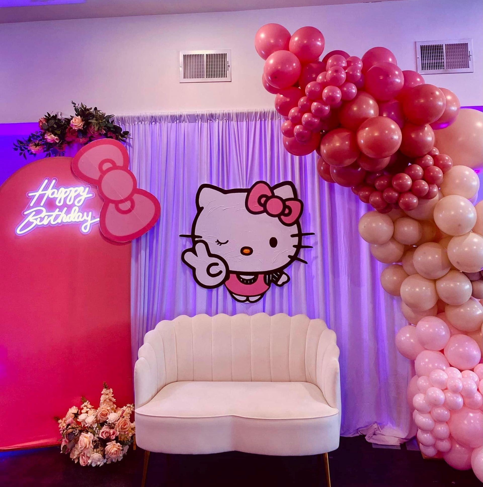 A room decorated with pink balloons and a hello kitty sign