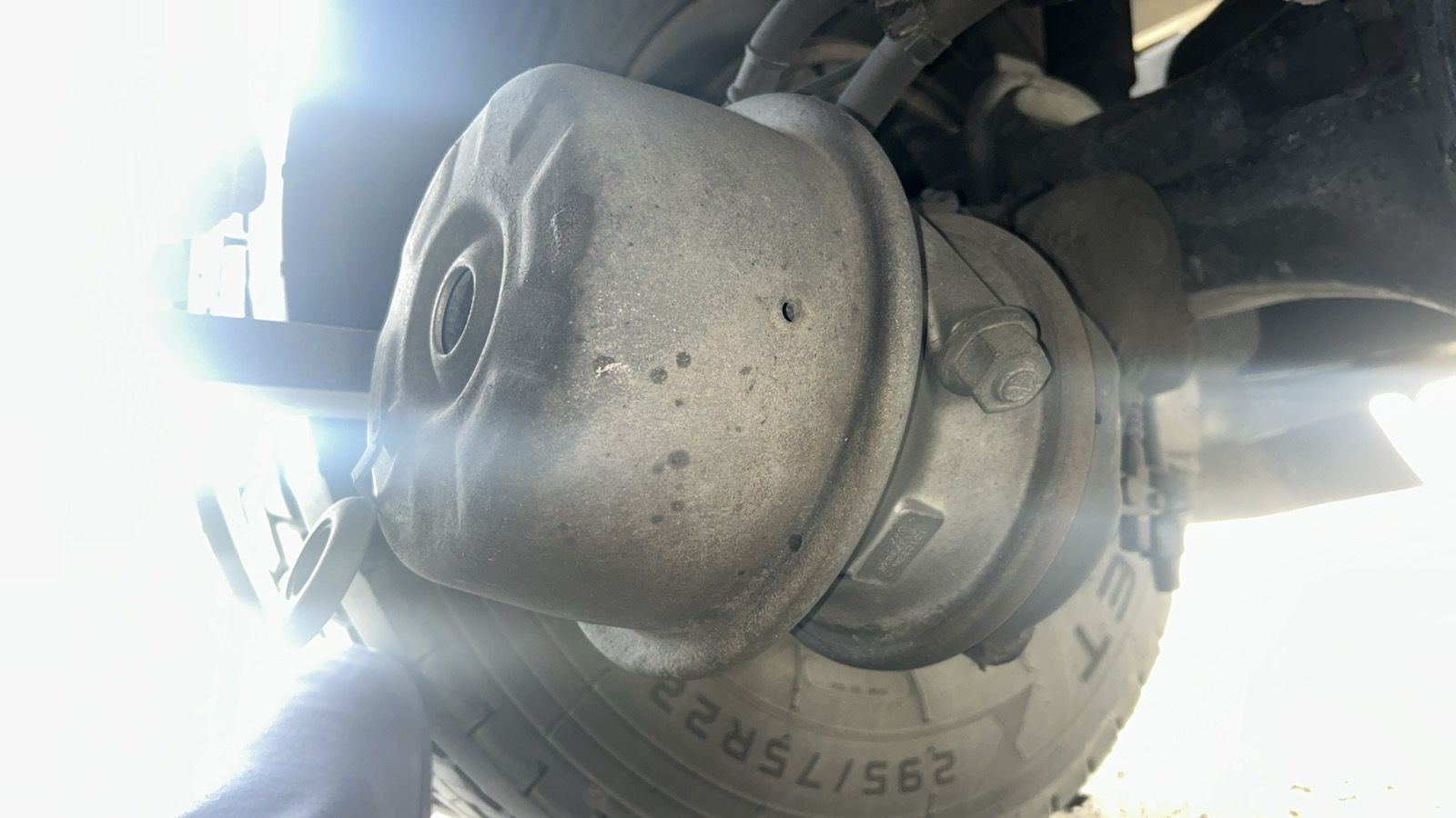 Close-up of a dusty vehicle wheel hub and tire undercarriage