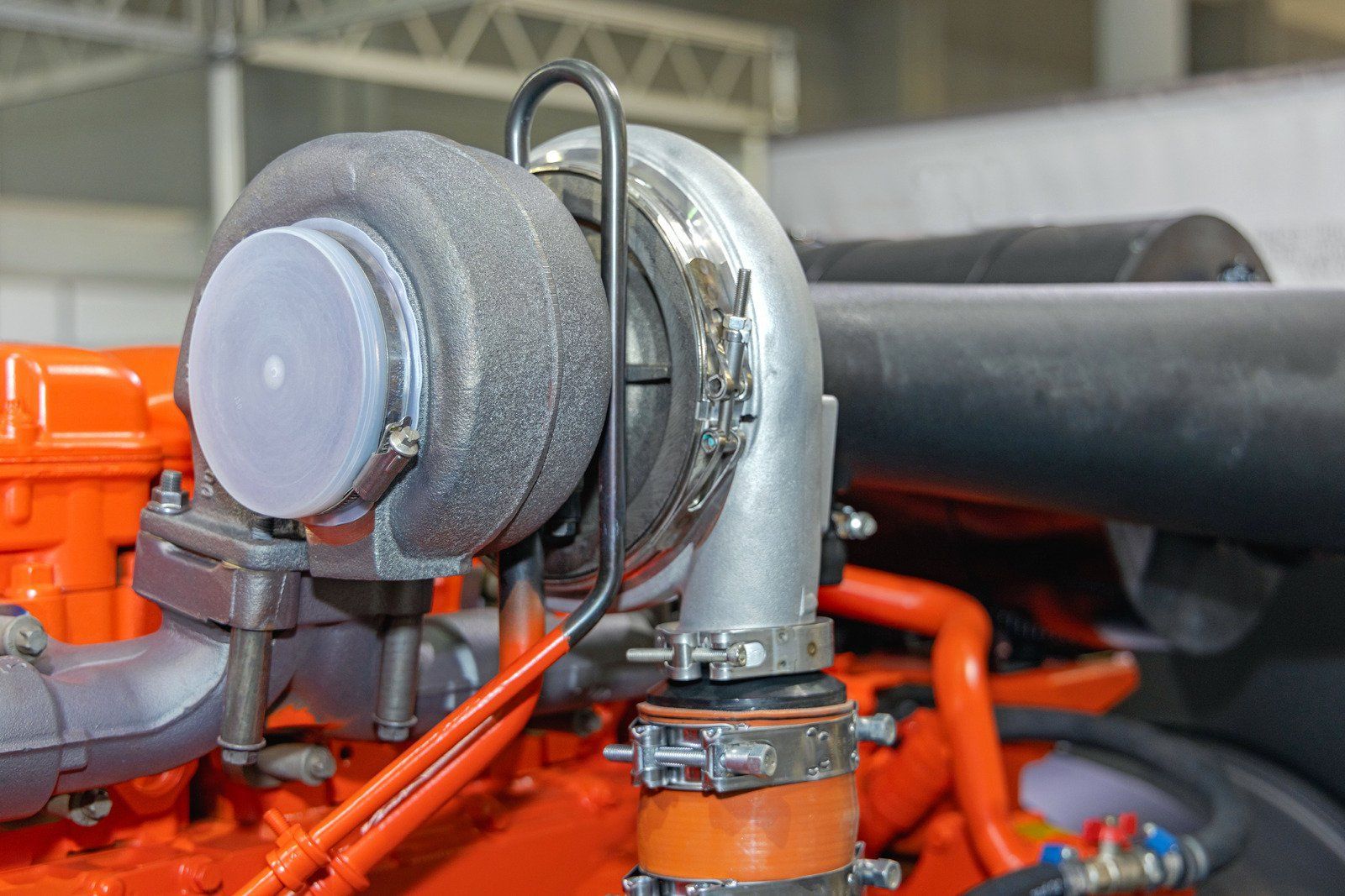 Close-up of a turbocharger and orange engine pipes in a car engine bay