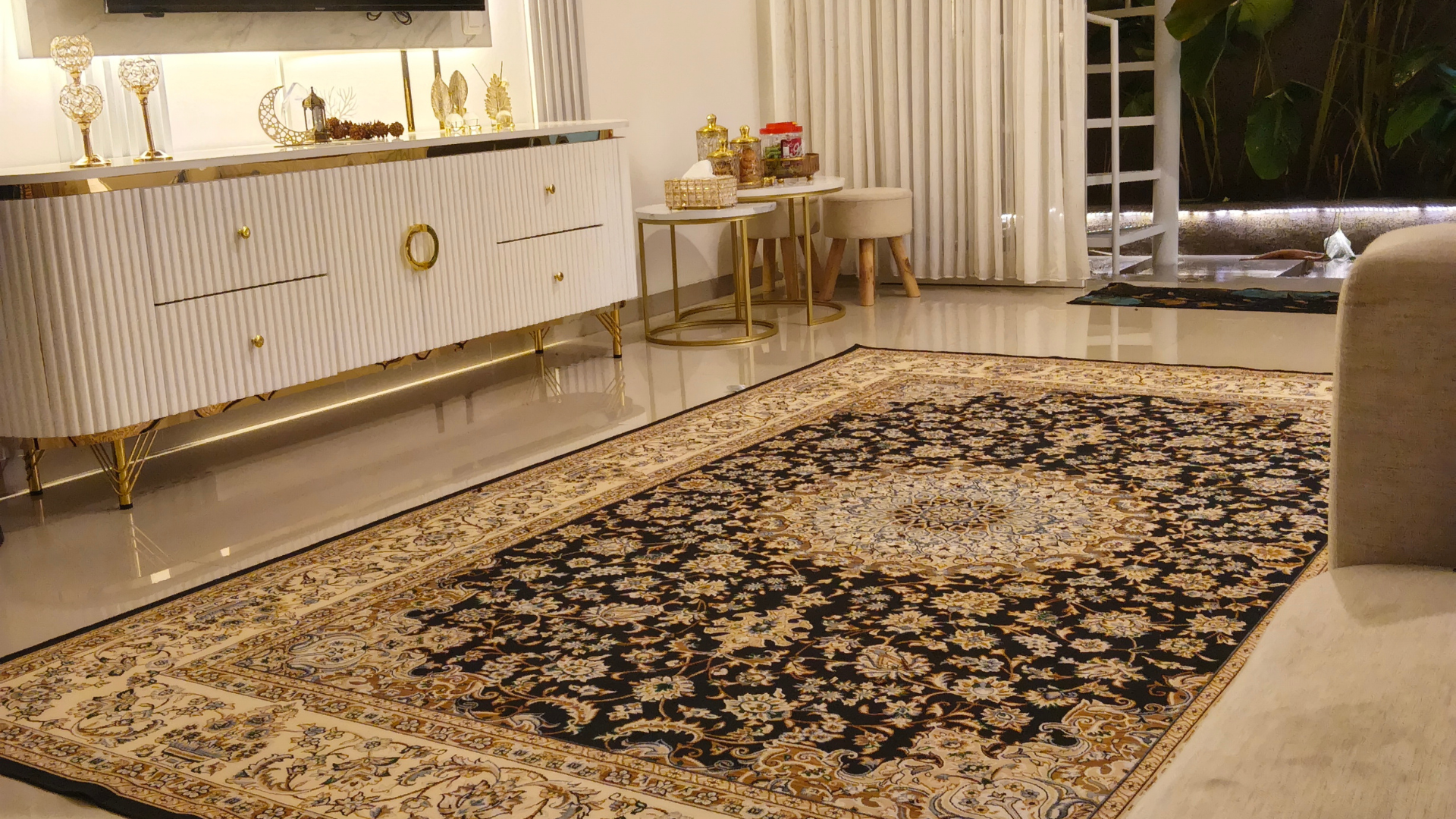 Elegant living room with ornate beige-and-black rug, white sideboard, curtains, and sofa armchair